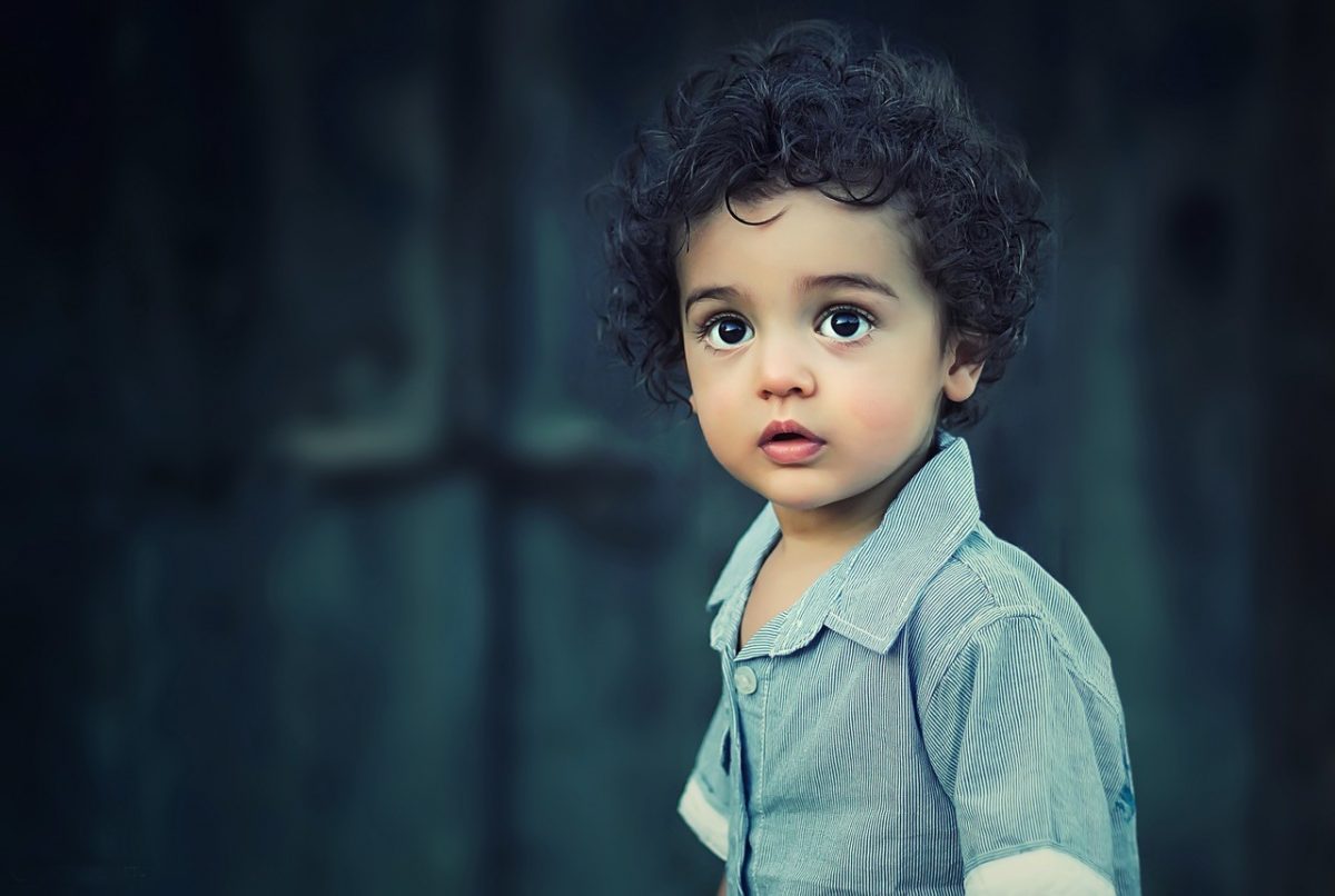 a young child with curly hair and a blue shirt