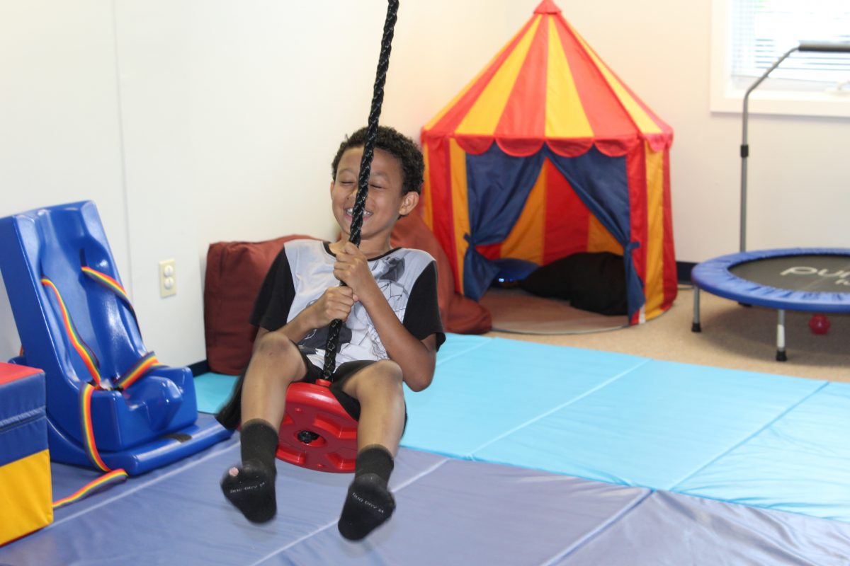 child on swing in physical therapy center