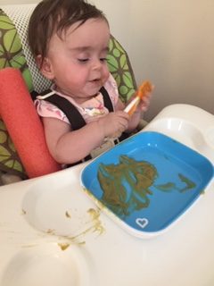 Infant positioned in high chair while being fed