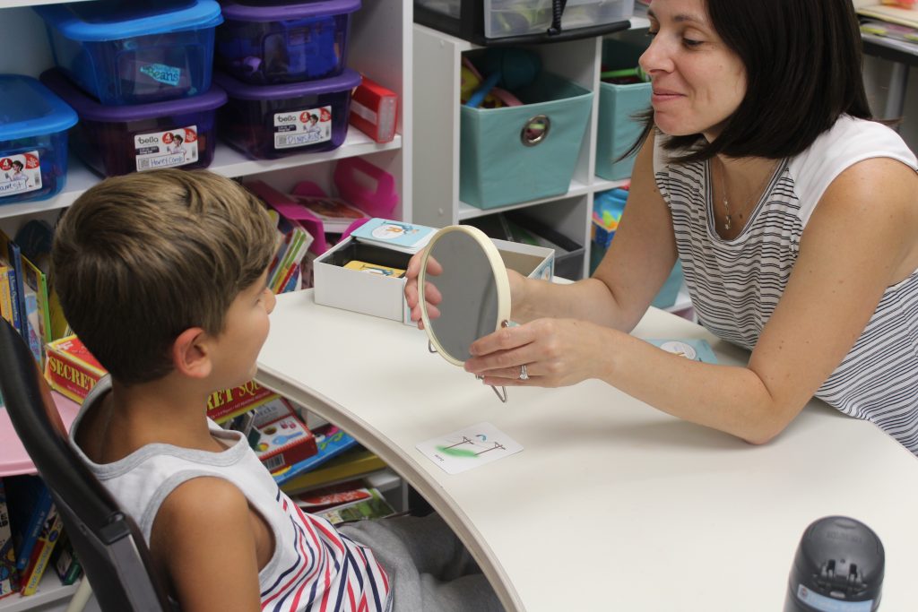 Speech therapist working with boy on fixing his stutter.