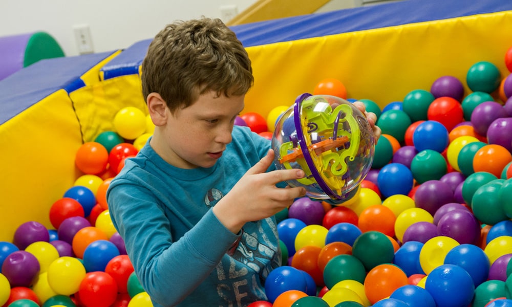 young boy playing with toys in ball pit