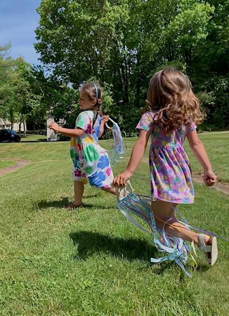 Children running in yard with hand kites