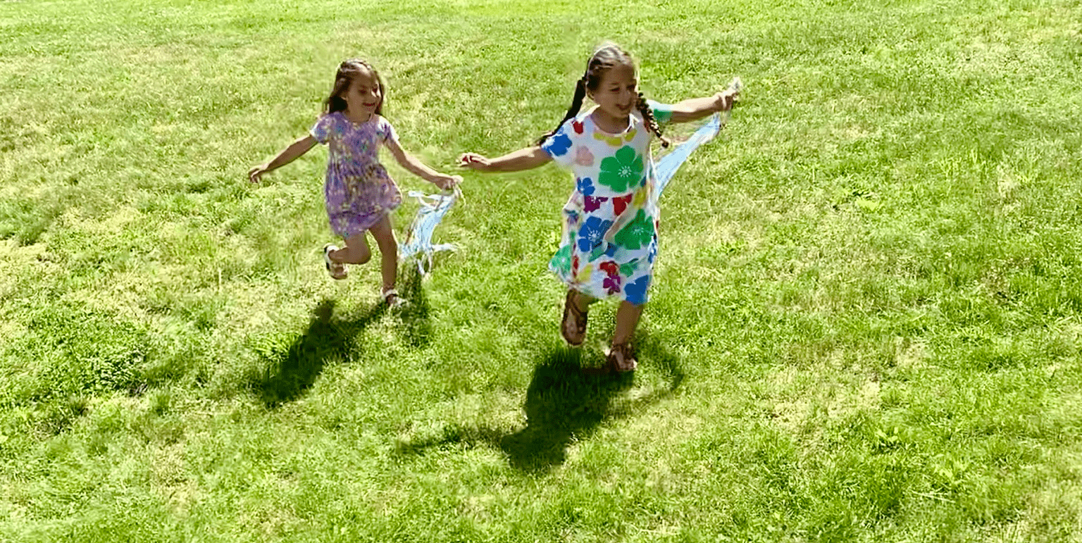 Children running in yard with hand kites