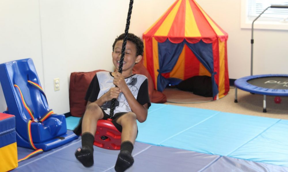 child on swing in physical therapy center