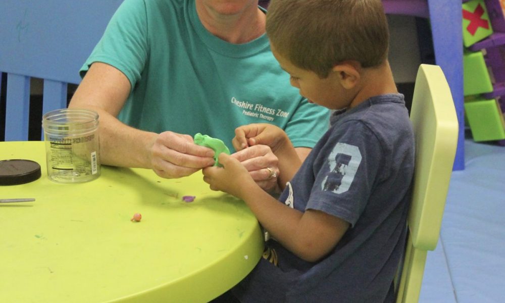 occupational therapist using play doh to treat child