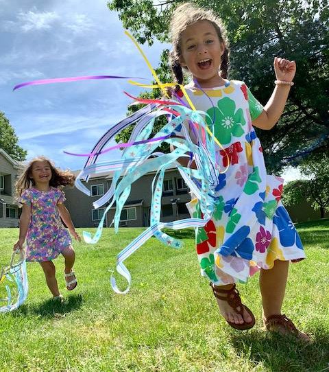 Children running in yard with hand kites