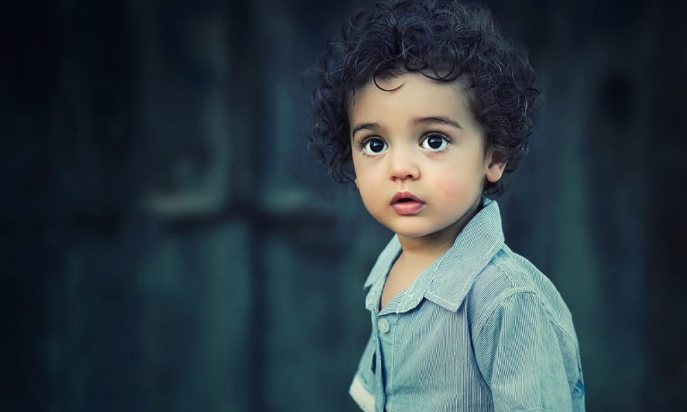 a young child with curly hair and a blue shirt